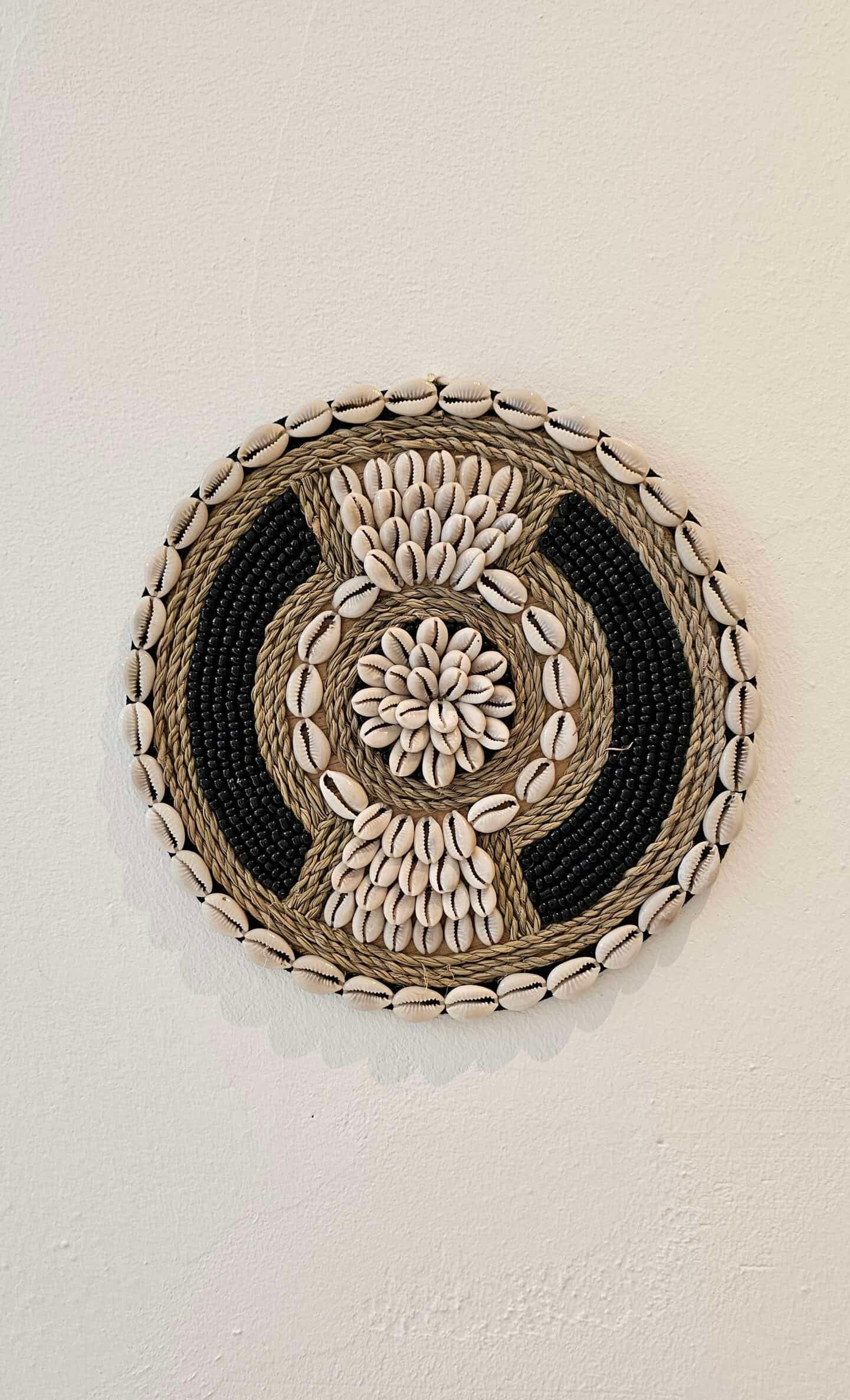 ronde boho wanddecoratie in de kleuren beige en zwart van kralen en schelpen