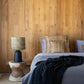 zwarte tafellamp met raffia lampenkap op houten bijzettafel in slaapkamer.