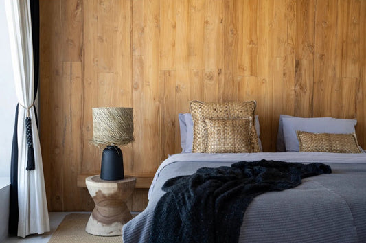 zwarte tafellamp met raffia lampenkap op houten bijzettafel in slaapkamer.