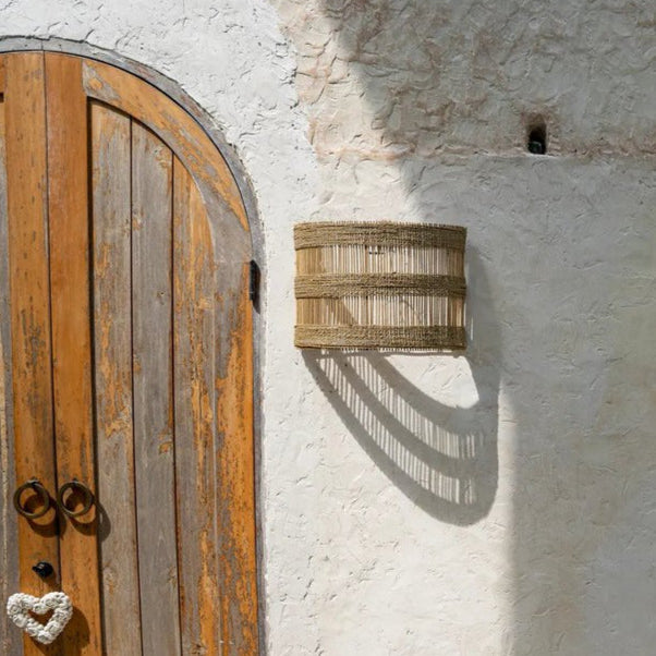 rotan wandlamp hangt aan stenen muur