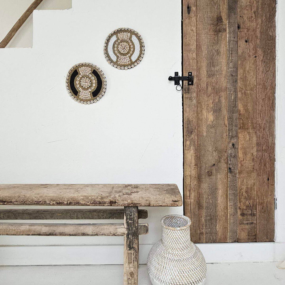 Ronde wanddecoratie van kralen en schelpen in de kleuren wit en beige.