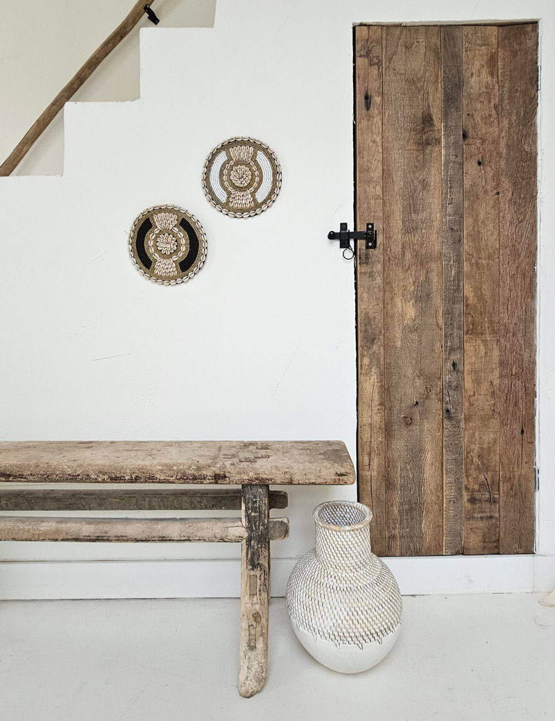 Ronde wanddecoratie van kralen en schelpen in de kleuren wit en beige.