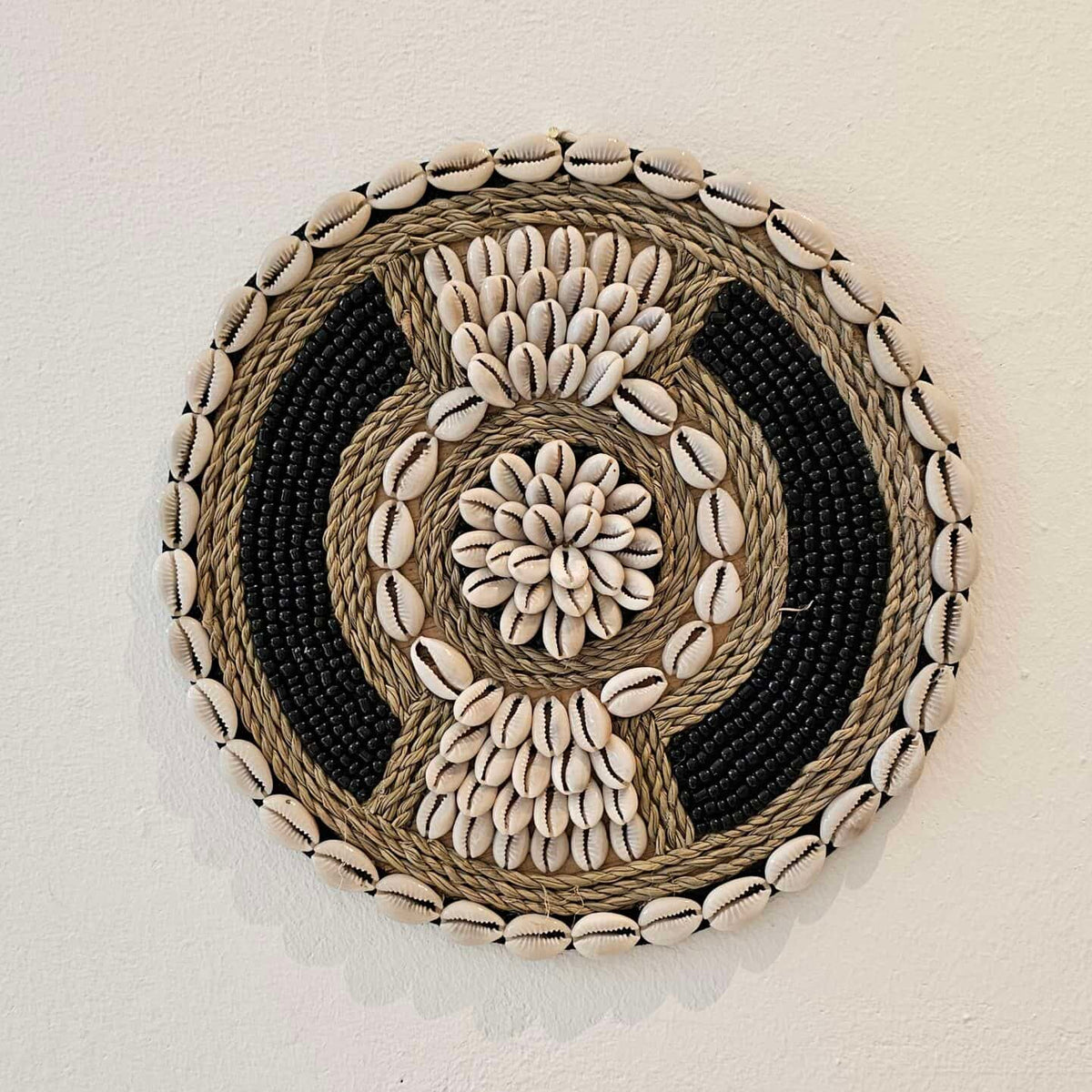 ronde boho wanddecoratie in de kleuren beige en zwart van kralen en schelpen