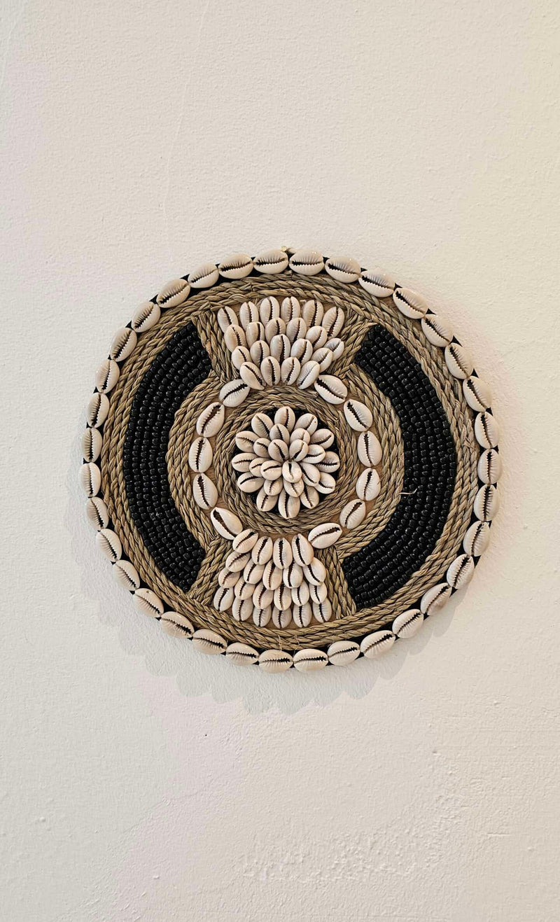 ronde boho wanddecoratie in de kleuren beige en zwart van kralen en schelpen