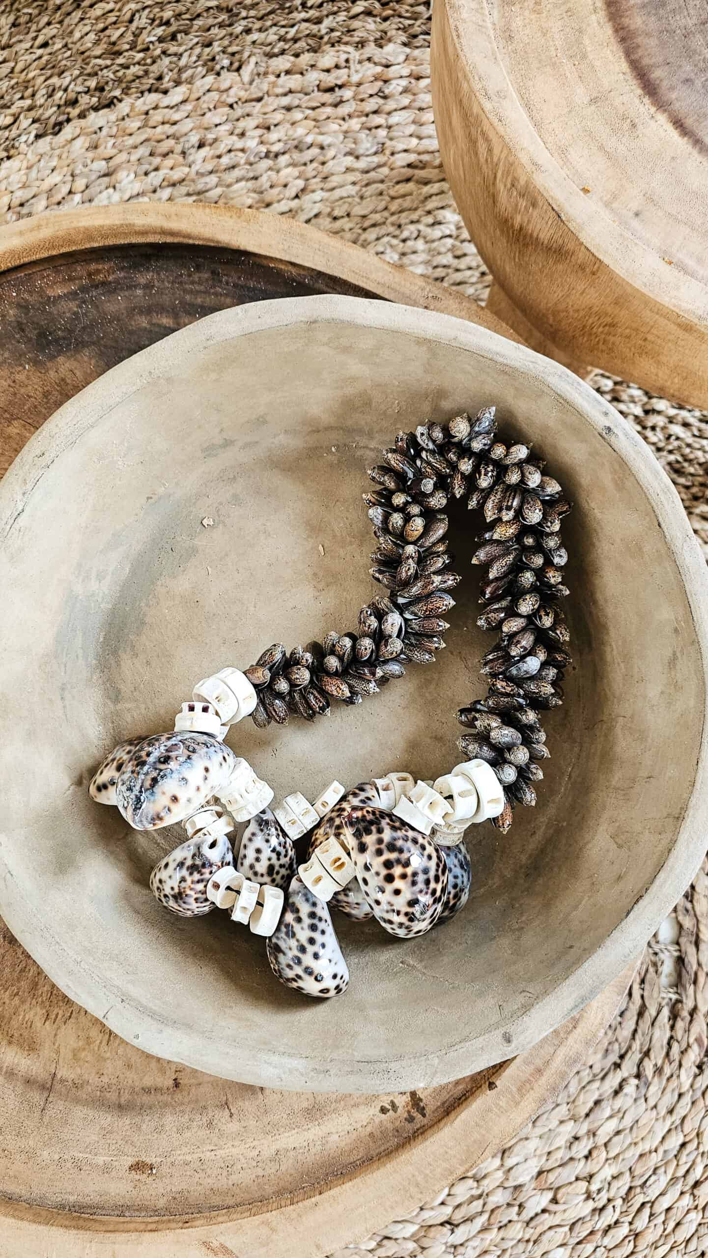 Boho woonketting gemaakt van schelpen ligt in terracotta schaal