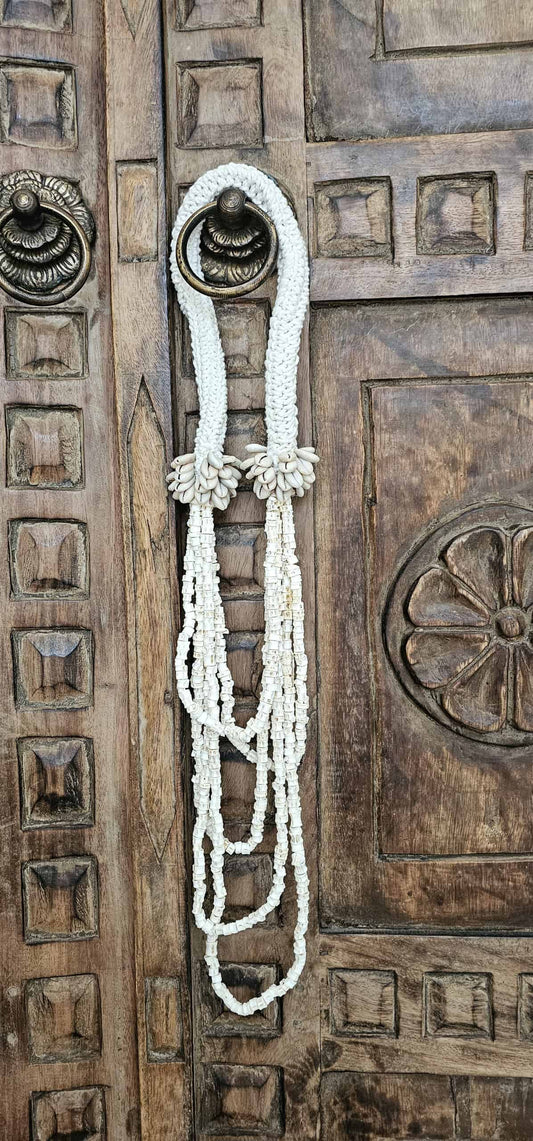 woonketting gemaakt van witte schelpen hangt aan Balinese deur