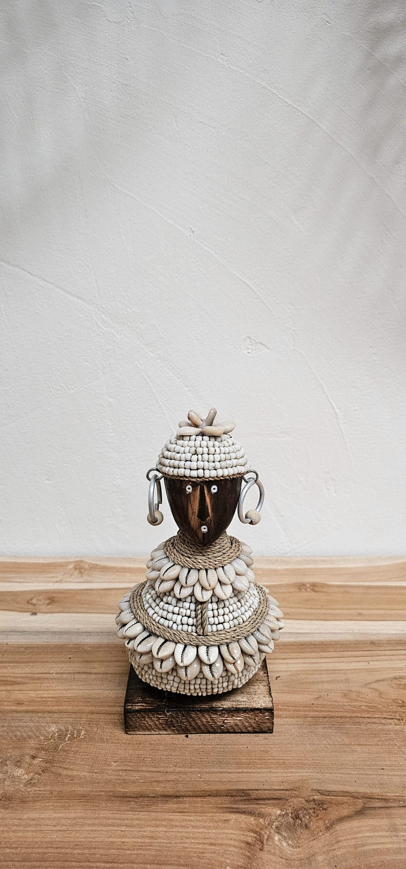 Handgemaakt Afrikaanse beeldje met schelpen staat op houten tafel