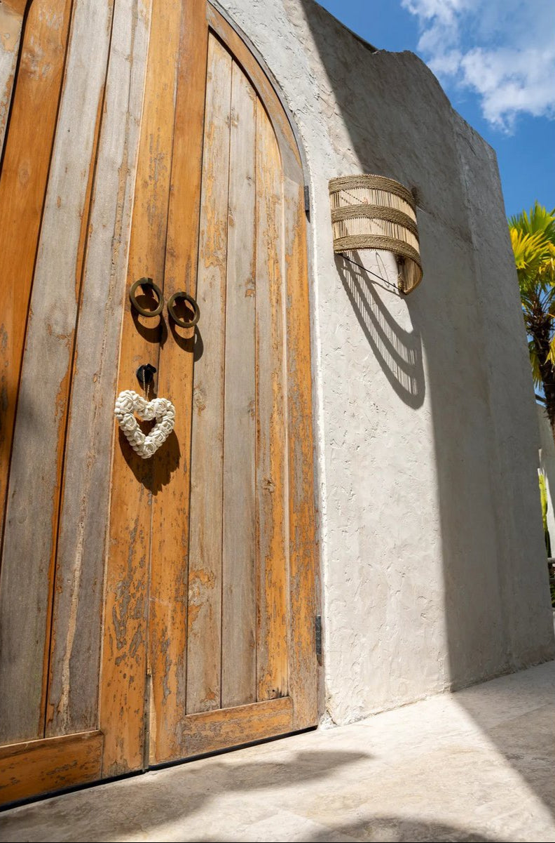 rotan hanglamp hangt naast houten deur