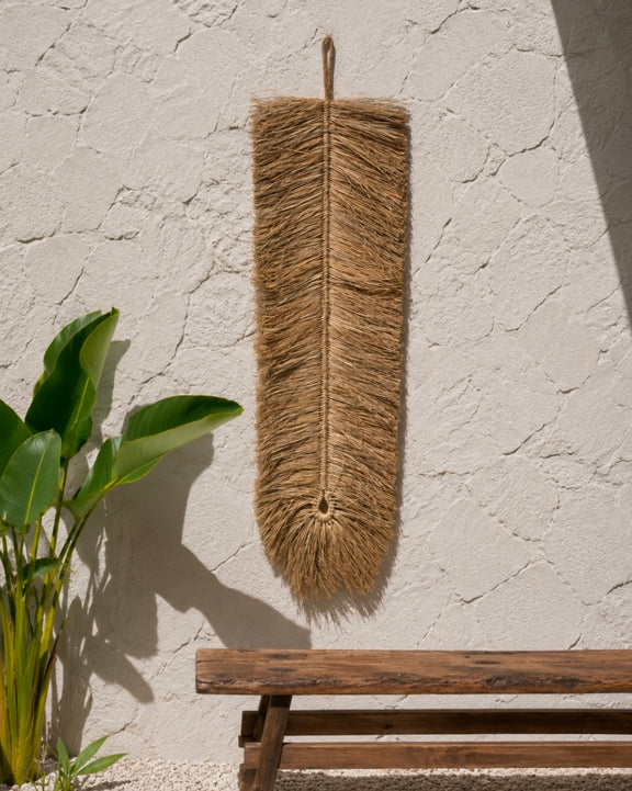 Lange boho wandhanger van raffia boven houten bank