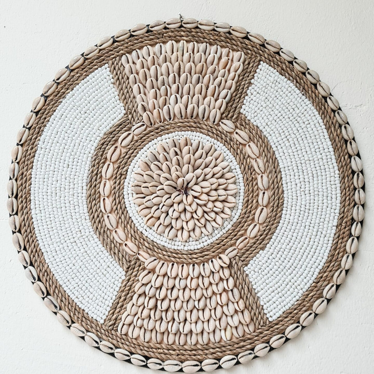 ronde boho wanddecoratie in de kleuren beige en wit van kralen en schelpen